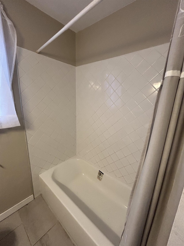 bathroom featuring shower / washtub combination, tile patterned flooring, and baseboards