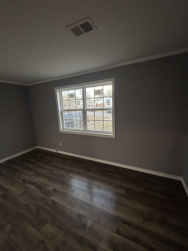 empty room featuring baseboards, dark wood-style flooring, visible vents, and crown molding