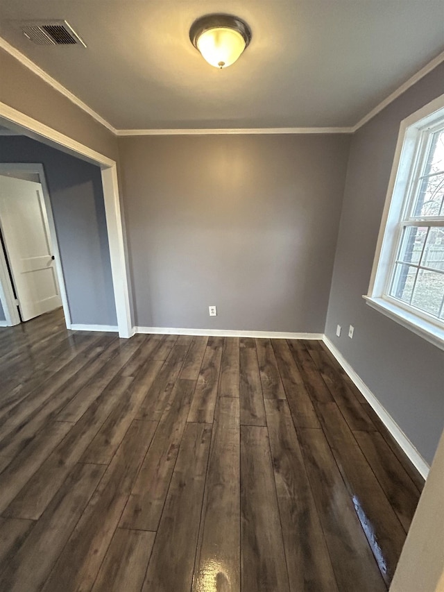 empty room with baseboards, dark wood-style flooring, visible vents, and crown molding