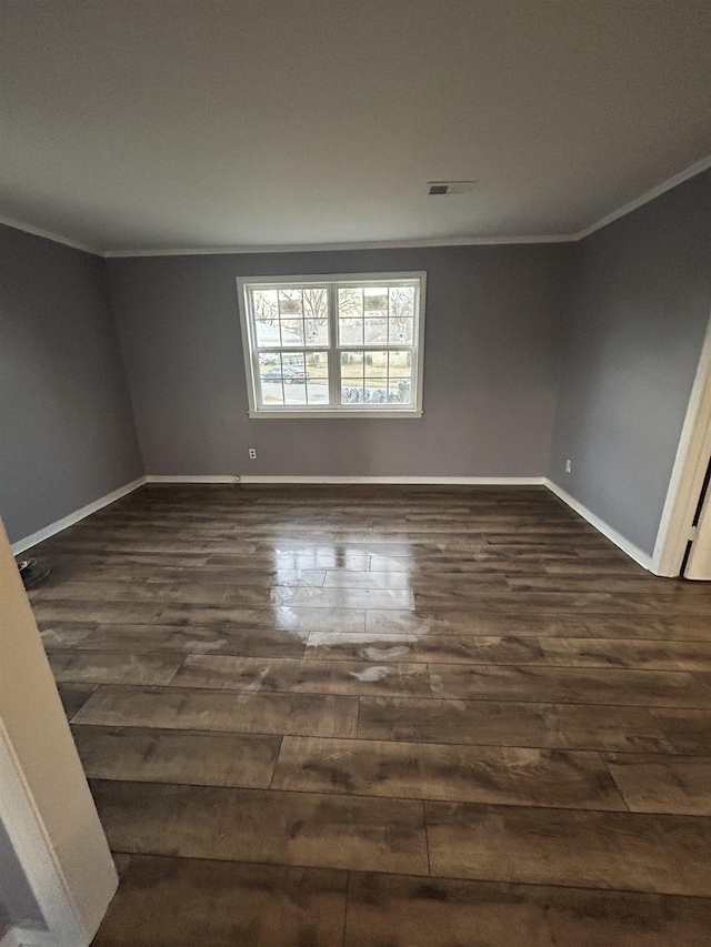 spare room featuring dark wood-style flooring and crown molding