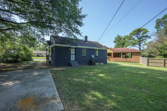 back of house with brick siding, a chimney, a lawn, crawl space, and fence