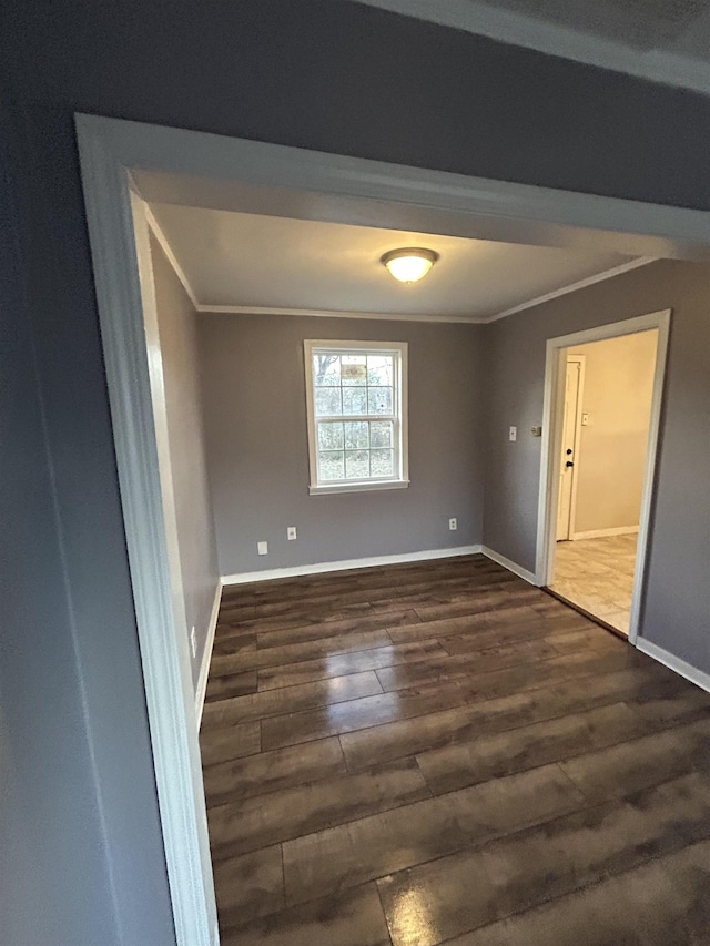 spare room with ornamental molding, dark wood-type flooring, and baseboards