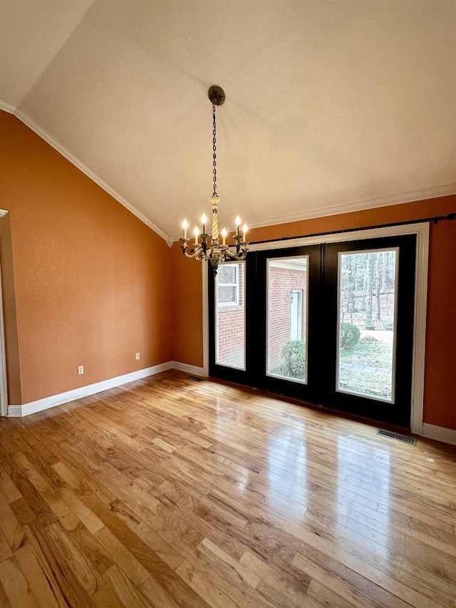 spare room featuring lofted ceiling, a notable chandelier, crown molding, and light wood-style flooring