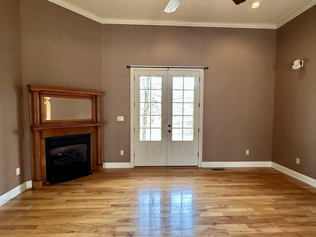 interior space with french doors, ornamental molding, a glass covered fireplace, and light wood-style flooring