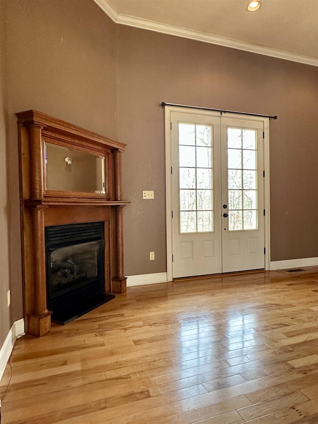 doorway with ornamental molding, a glass covered fireplace, french doors, and light wood finished floors