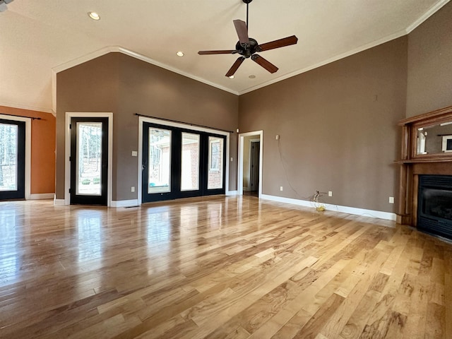 unfurnished living room with ornamental molding, light wood-type flooring, a glass covered fireplace, and baseboards