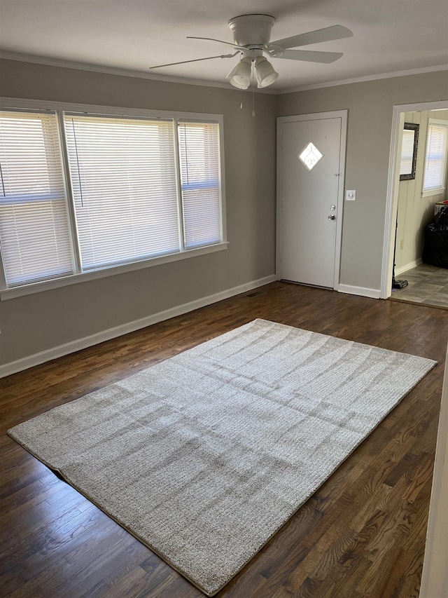 foyer entrance featuring crown molding, dark wood-type flooring, a ceiling fan, and baseboards