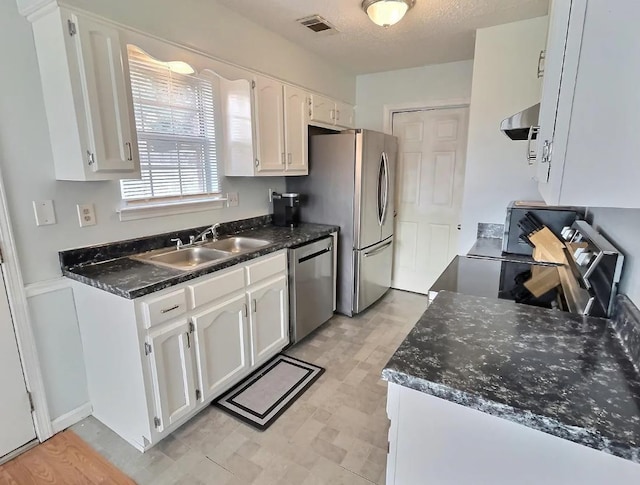 kitchen featuring a sink, visible vents, white cabinetry, appliances with stainless steel finishes, and range hood