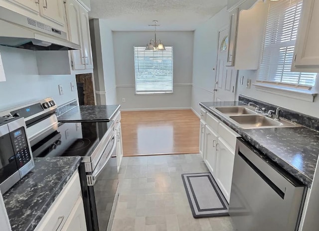 kitchen featuring dark countertops, under cabinet range hood, appliances with stainless steel finishes, and a sink