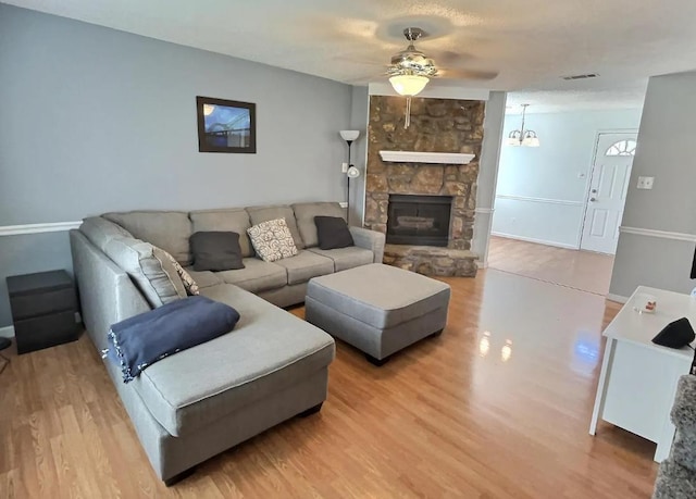 living area featuring ceiling fan, light wood-style flooring, a fireplace, and visible vents