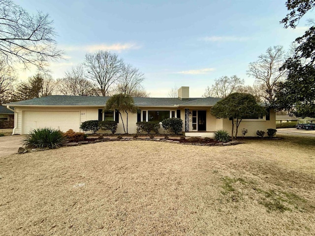 ranch-style house featuring a garage, a chimney, concrete driveway, and a front lawn