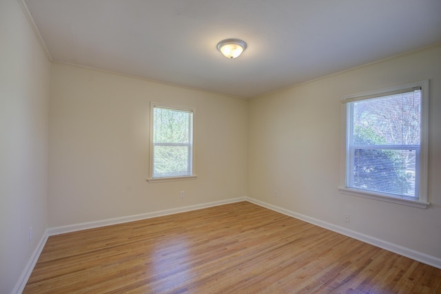 unfurnished room with plenty of natural light, light wood-style flooring, crown molding, and baseboards
