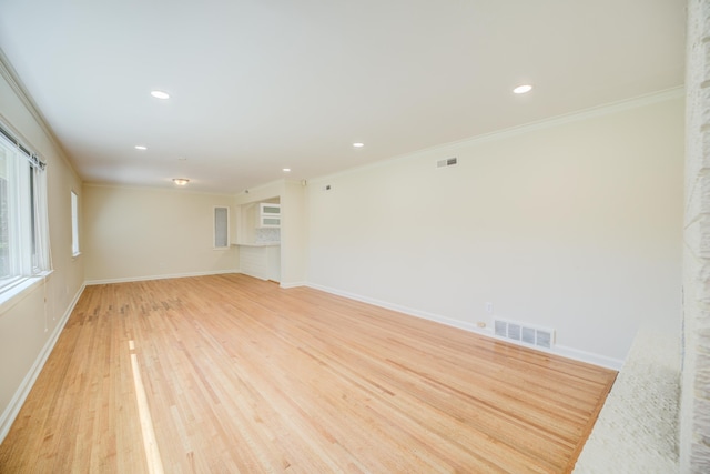spare room featuring visible vents, baseboards, crown molding, and light wood-style floors