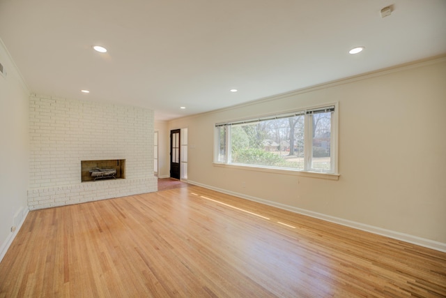 unfurnished living room with crown molding, baseboards, recessed lighting, a fireplace, and wood finished floors