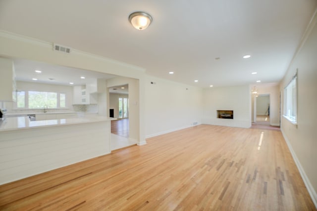 unfurnished living room with visible vents, baseboards, a fireplace, and light wood finished floors
