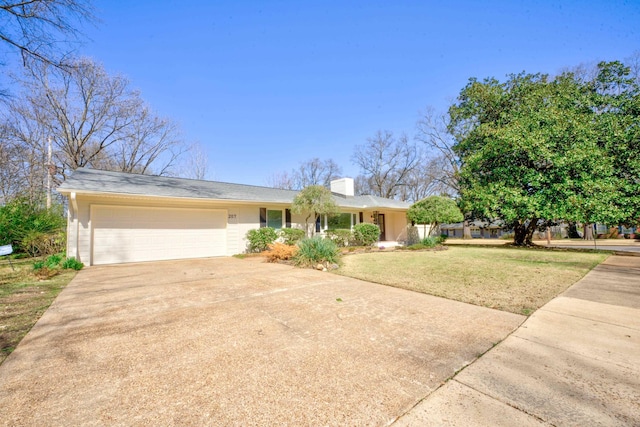 ranch-style house featuring a front lawn, a chimney, concrete driveway, and an attached garage