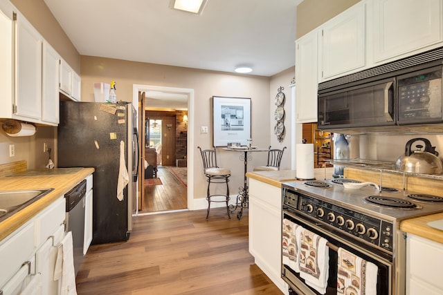 kitchen featuring baseboards, white cabinets, light wood-style flooring, and black appliances