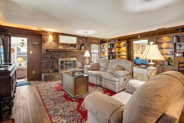 living room featuring a textured ceiling, hardwood / wood-style flooring, wood walls, a fireplace, and visible vents