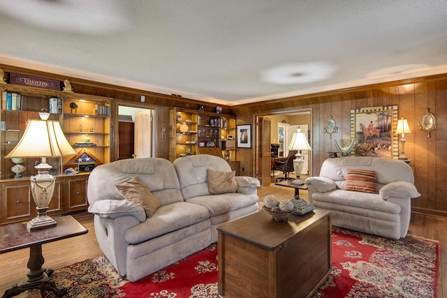 living area featuring crown molding, wood walls, a textured ceiling, and wood finished floors