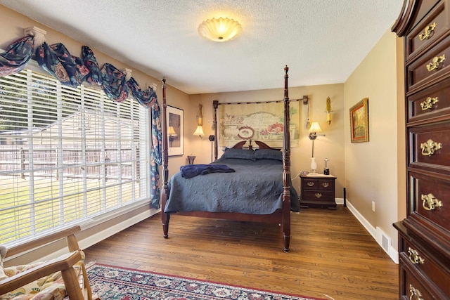 bedroom featuring visible vents, a textured ceiling, baseboards, and hardwood / wood-style flooring