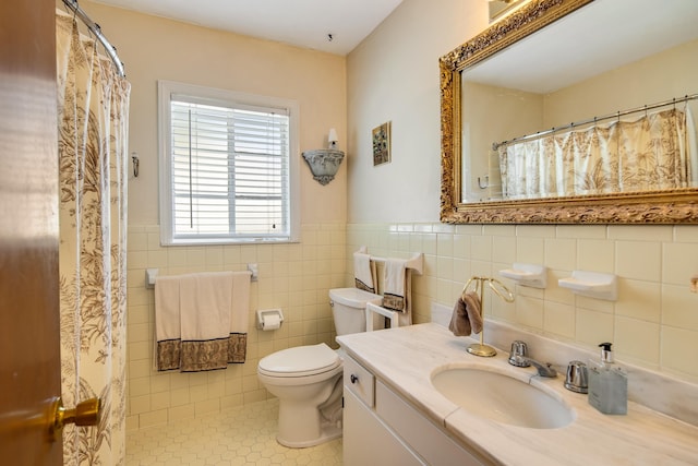 bathroom with tile patterned flooring, toilet, vanity, tile walls, and wainscoting