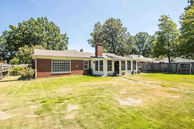 back of property featuring a fenced backyard, a lawn, and brick siding