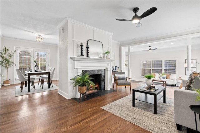 living area featuring a high end fireplace, crown molding, baseboards, and wood finished floors