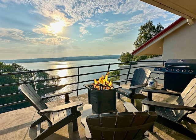 balcony featuring area for grilling, an outdoor fire pit, and a water view