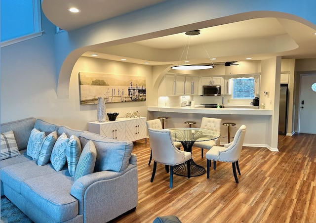 living area with recessed lighting, arched walkways, baseboards, and wood finished floors