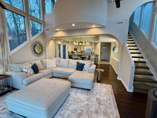 living area featuring arched walkways, dark wood-style flooring, and visible vents