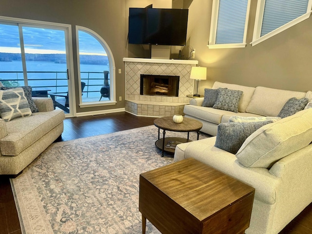 living room featuring a tile fireplace, baseboards, and wood finished floors
