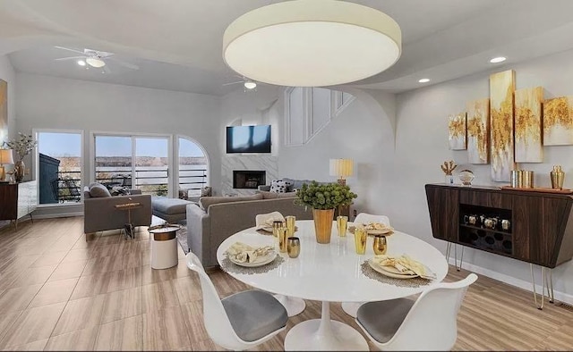 dining room featuring baseboards, a premium fireplace, a ceiling fan, and recessed lighting