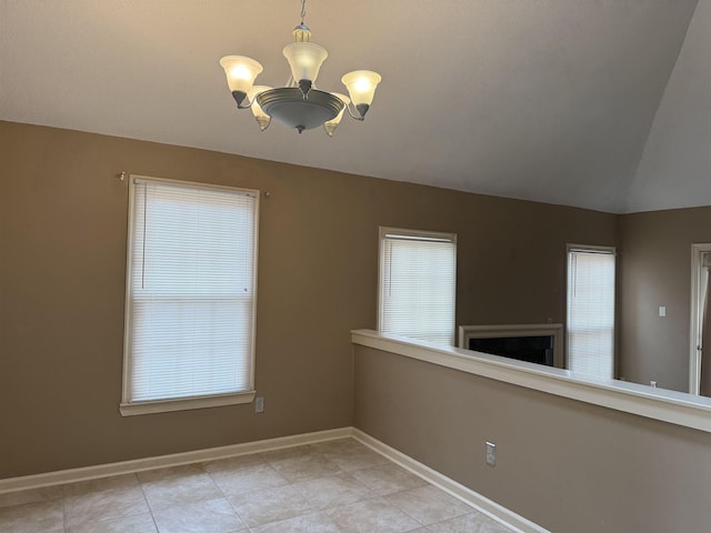 empty room with plenty of natural light, a notable chandelier, lofted ceiling, and baseboards