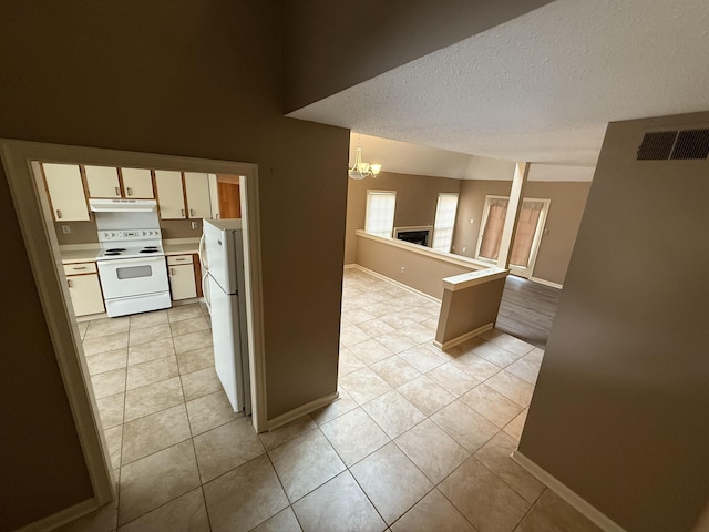 kitchen featuring under cabinet range hood, white appliances, visible vents, open floor plan, and light countertops