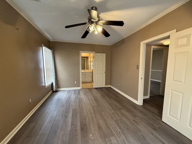 unfurnished bedroom featuring dark wood-style floors, ensuite bathroom, a ceiling fan, ornamental molding, and baseboards