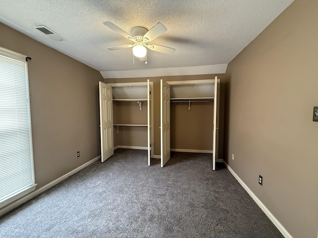 unfurnished bedroom with multiple closets, visible vents, a textured ceiling, and baseboards