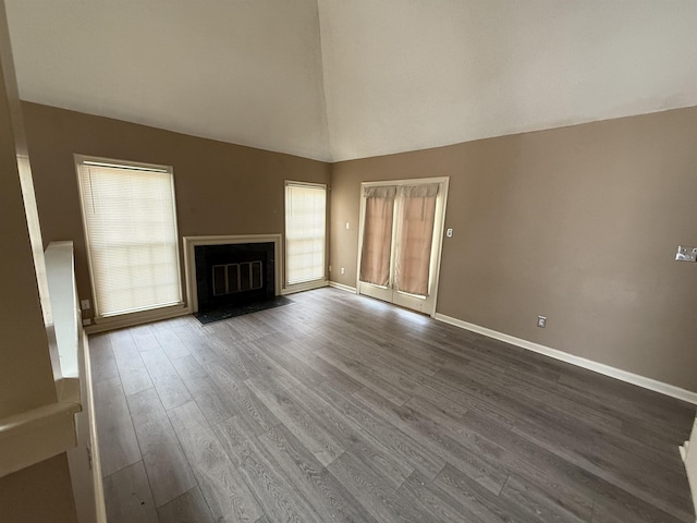 unfurnished living room with dark wood-type flooring, baseboards, high vaulted ceiling, and a fireplace with flush hearth