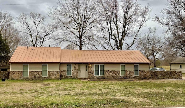 view of front of home featuring metal roof, stone siding, and a front yard