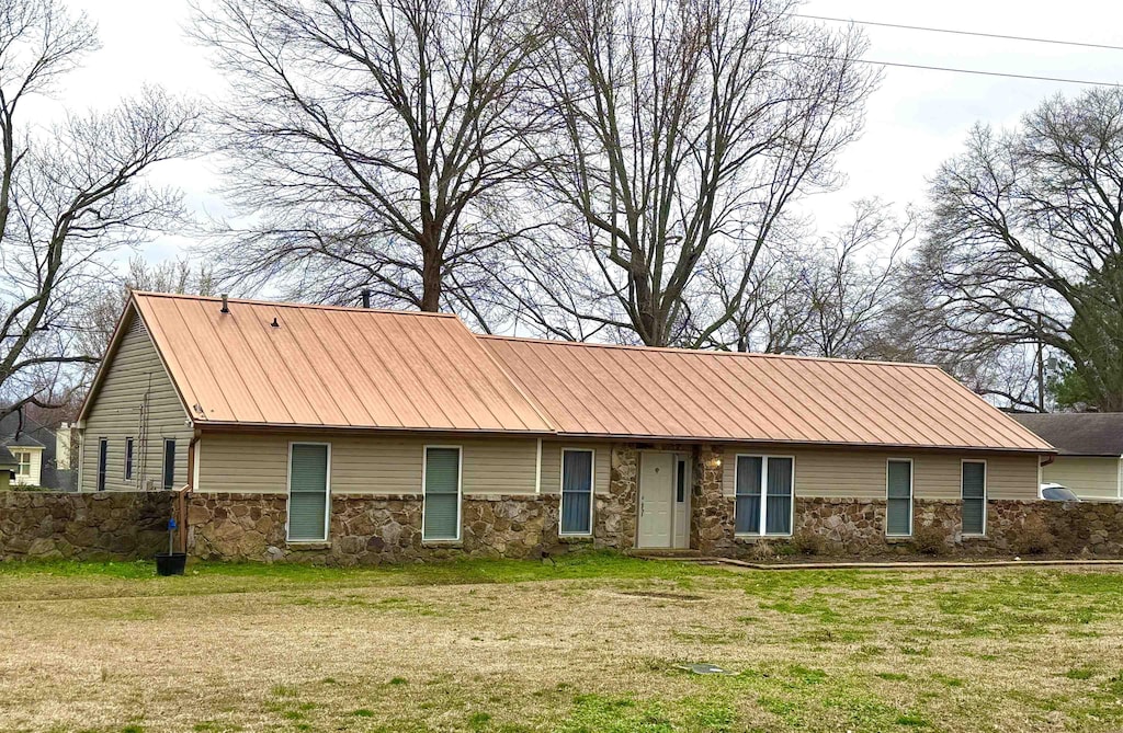 view of front of property with metal roof, stone siding, and a front lawn