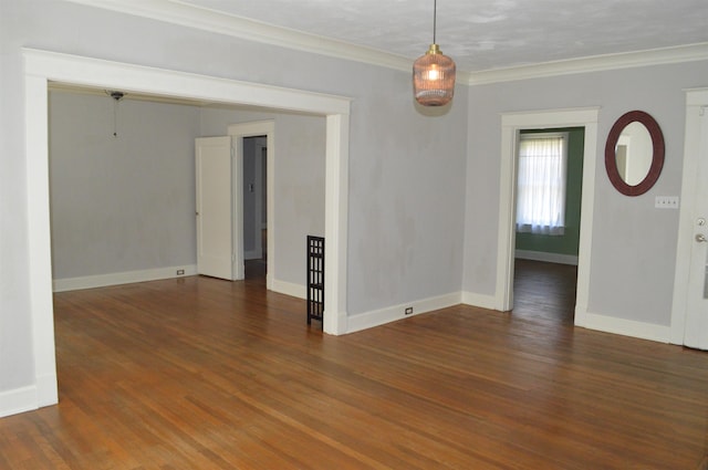 empty room with baseboards, crown molding, and wood finished floors