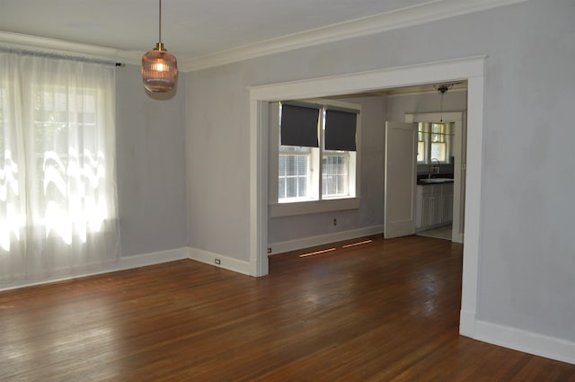 empty room with ornamental molding, dark wood finished floors, a sink, and baseboards