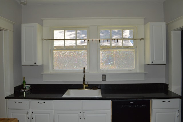 kitchen with dark countertops, white cabinets, dishwasher, and a sink