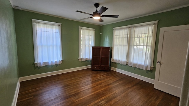 unfurnished bedroom featuring ornamental molding, dark wood finished floors, a ceiling fan, and baseboards