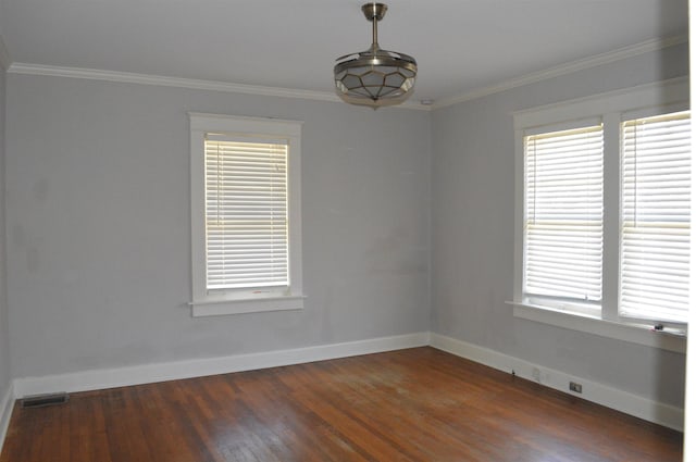 empty room with ornamental molding, visible vents, baseboards, and dark wood-style floors