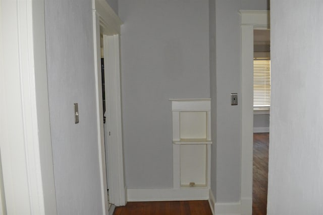 hallway featuring dark wood-type flooring and baseboards