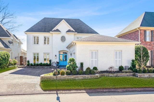 french country inspired facade with brick siding, a shingled roof, and french doors