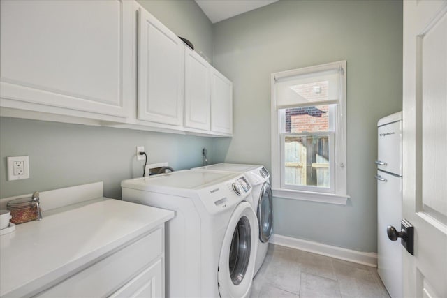 washroom with cabinet space, baseboards, washer and clothes dryer, and light tile patterned flooring