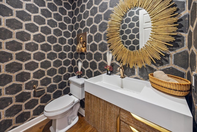 half bathroom featuring a sink, toilet, and wood finished floors