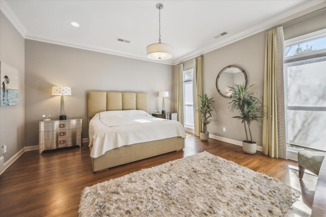 bedroom with ornamental molding, visible vents, baseboards, and wood finished floors