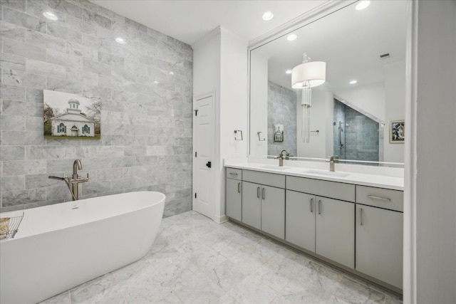 full bath featuring double vanity, a soaking tub, a sink, marble finish floor, and tile walls